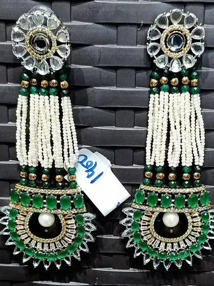 A unique pair of long, hanging earrings with green and white beads, pearls, and kundan work.