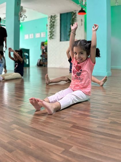 The pure joy of movement. A student in our Powerpuff Beginners class raises her hands with a big smile, showing the confidence and happiness we nurture in our studio.