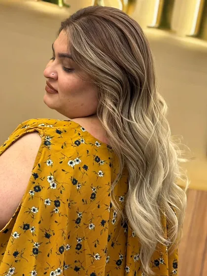 A beautiful balayage transformation, with a seamless melt from dark roots to light, ash-blonde ends, styled in long, flowing waves.