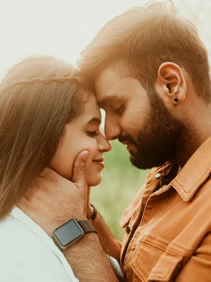 A tender and intimate close-up of a couple, their faces close together in a moment of quiet connection. The warm, soft light enhances the romantic mood of the portrait.