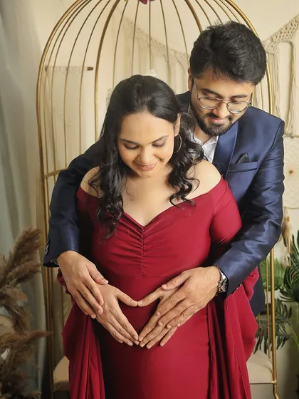 A classic couple's pose where both partners gently hold the baby bump, forming a heart with their hands. It’s a simple yet powerful way to symbolize their love for the baby.