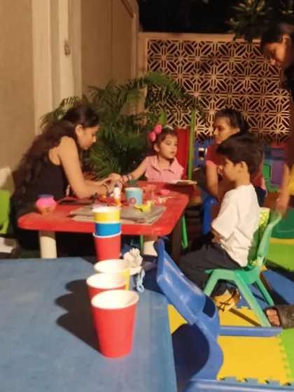 A candid shot of the art and craft corner, showing children interacting and creating together in a safe and fun environment.