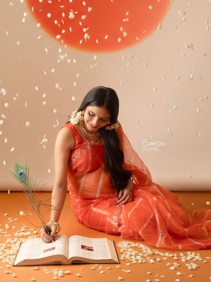 A creative pose where the mother to be writes in a book with a peacock feather. This artistic shot symbolizes the story they are beginning to write as a family.
