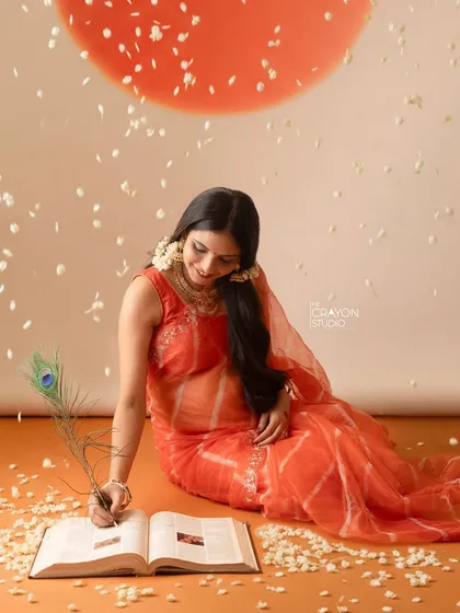 A creative pose where the mother to be writes in a book with a peacock feather. This artistic shot symbolizes the story they are beginning to write as a family.