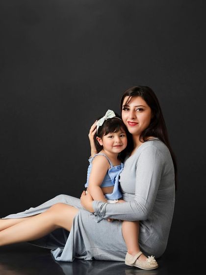 A tender moment between a mother and her daughter. This classic portrait against a dark, reflective floor highlights their close bond and affection.