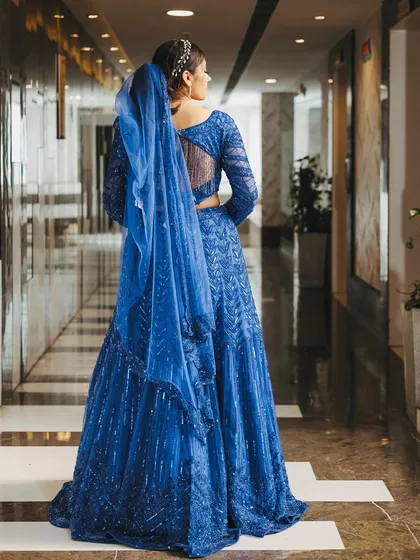 A view of the back of the royal blue lehenga, showing the sheer panel and detailed embroidery that continues around the entire outfit.