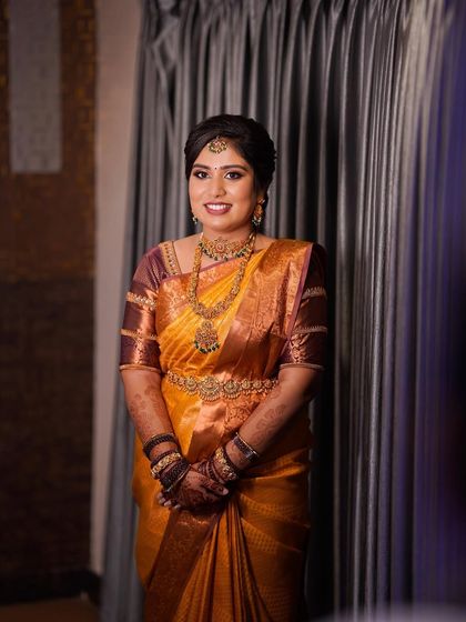 A solo portrait of the happy client. Her makeup is warm and glowing, perfectly complementing her mustard yellow saree.