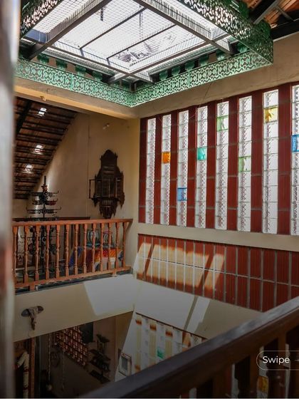 A view from the upper level of the Padmaja Rao Residence, looking down at the courtyard through a screen of colored glass blocks and a decorative metal railing.