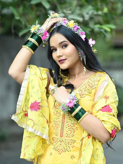 A confident and happy Haldi bride. The floral crown and matching hand jewelry are the stars of this look, complemented by fresh and simple makeup.