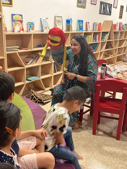 An instructor demonstrates how to use a hand puppet, capturing the children's attention and sparking their imagination for the stories they will soon create.