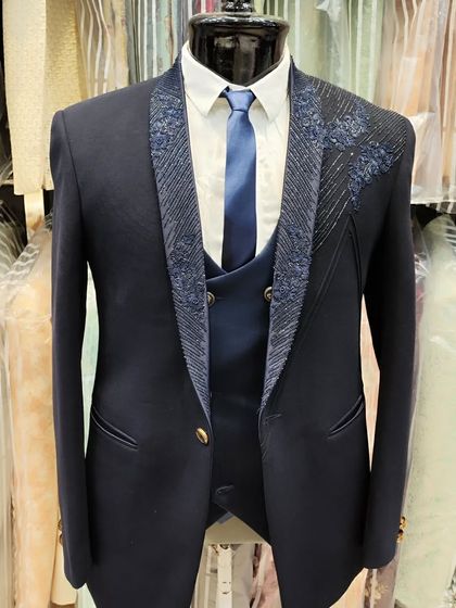 A clear, full view of the hand embroidered navy blue groom's suit on a mannequin, highlighting the craftsmanship.