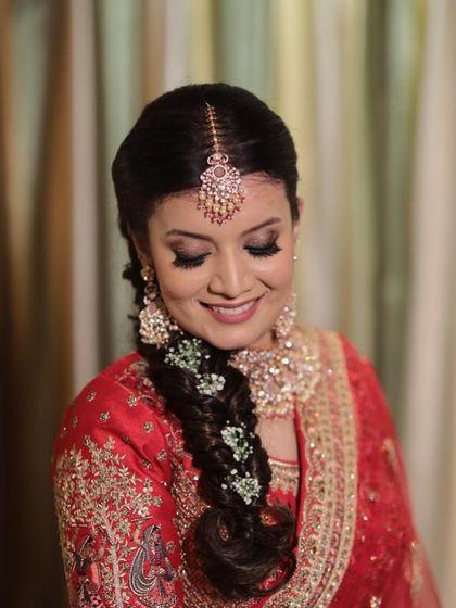 A close-up of this smiling bride. Her makeup is soft and glowing, with a braided hairstyle that is both intricate and perfect for dancing the night away at her sangeet.