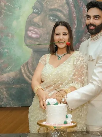 A joyous cake-cutting moment during an indoor engagement celebration in Pune. The couple's happiness is the focus, framed by modern decor and a beautiful piece of art, capturing the celebratory spirit of the occasion.