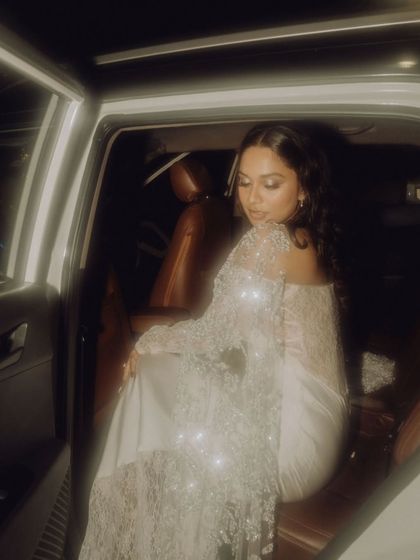 A glamorous shot of the bride in her sparkling white gown, sitting in a car, the light catching the sequins perfectly.