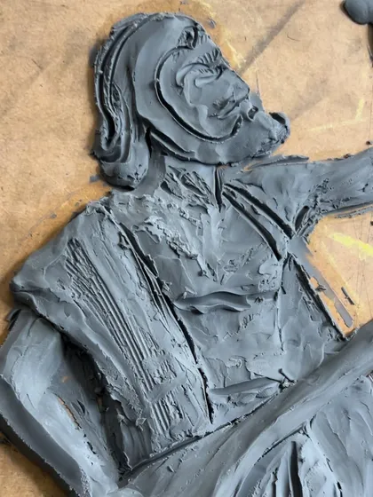A close-up view of the clay work, detailing the texture on the clothing and the form of the torso of the Kanaka Dasa figure.
