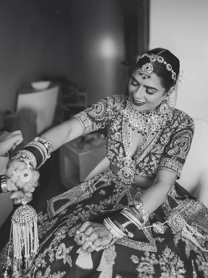 A black and white shot of the bride getting her 'kalire' tied, a traditional and emotional moment captured beautifully.
