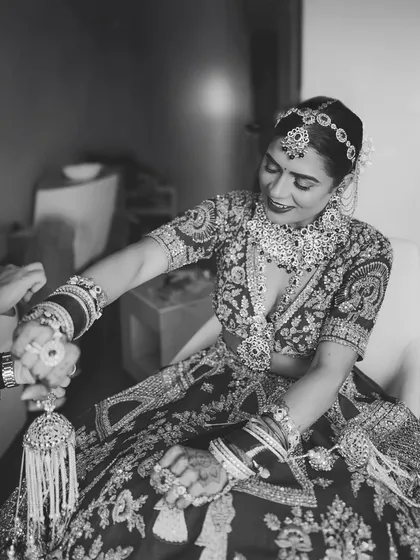 A black and white shot of the bride getting her 'kalire' tied, a significant and emotional pre-wedding ritual.
