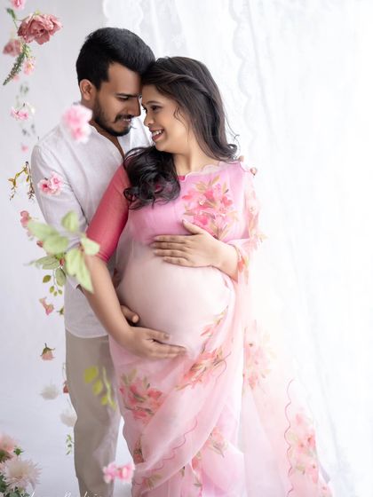 A sweet and loving portrait. The couple embraces, their shared happiness evident in their smiles. The floral saree adds a touch of modern romance to the traditional look.