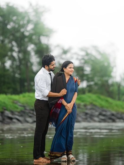This photo captures a classic, retro-inspired moment by the water. The traditional saree and the protective gesture from him create a timeless image that feels like a scene from an old movie.