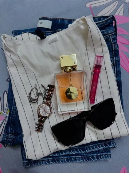 This flat lay captures the essence of a perfect weekend outfit. It’s built around comfortable jeans and a versatile waistcoat, with personal touches like your favorite perfume and lip gloss to make it your own.
