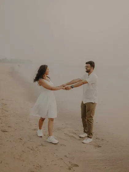 Dancing on the sand as the fog rolls in. This atmospheric pre-wedding shot captures a private, romantic moment between the couple on a quiet beach.