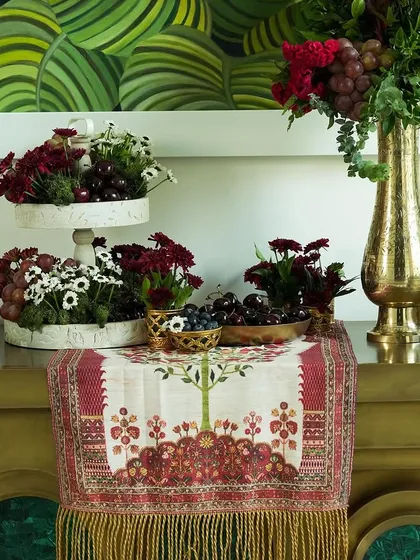 This tablescape shows how we mix different elements to create visual interest. Notice the tiered stands with flowers and fruits, the brass console, and the large art piece in the background, all working together.