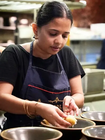 A female chef carefully assembling a dish, showing the focus and delicate touch required in a professional kitchen. This image celebrates the diverse talent behind great food.