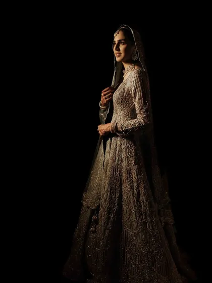 A dramatic portrait using the chiaroscuro technique. The play of light and shadow sculpts the bride's features and gown, creating a powerful, moody, and unforgettable image.