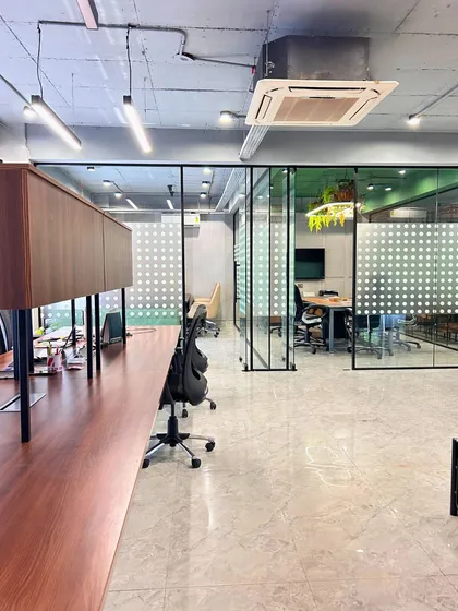 This view shows the open office layout with glass partitions that create a sense of transparency. The consistent use of materials and frosted glass patterns ensures a cohesive and professional look.