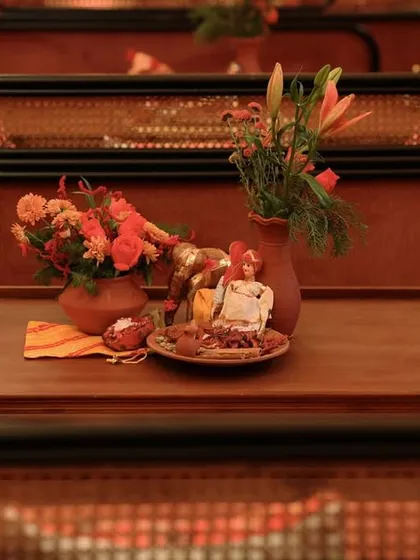 A tabletop detail featuring small Rajasthani dolls, clay pots with flowers, and a tray of spices, creating a scene full of character and local charm.