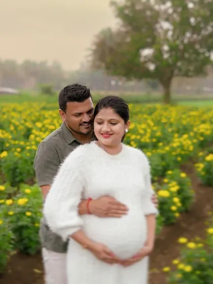 An outdoor couple's maternity shoot in a beautiful field of yellow flowers. These natural settings provide a relaxed and joyful backdrop for capturing your journey together.