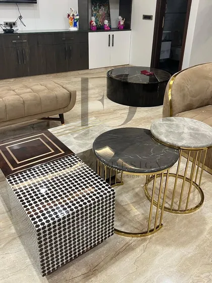 A collection of various custom tables, showcasing the diversity of my work. This includes a side table with a black and white bone inlay top and another set of nesting tables in marble and metal.