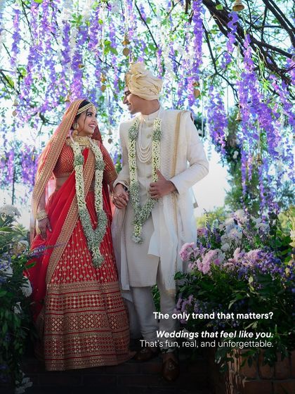 A beautiful couple stands under a canopy of purple wisteria. This image captures our core belief: the only trend that matters is a wedding that feels like you. We focus on creating fun, real, and unforgettable celebrations that tell your unique story.