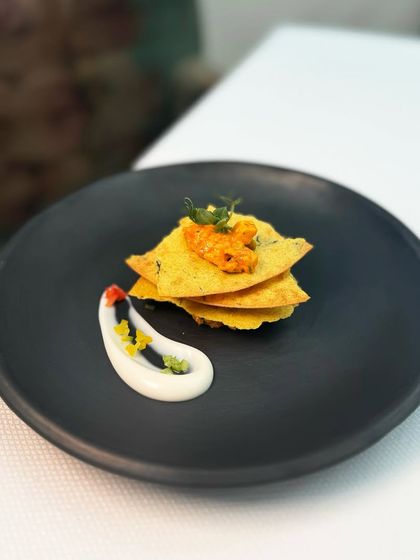 This is our paneer tikka chaat, served as a khakra mille-feuille with a dollop of Shimla mirch mayo. The layers of crisp khakra and flavourful paneer create a delightful textural experience.