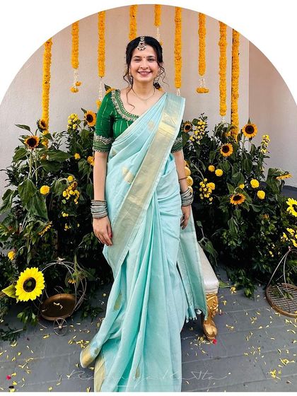 The full view of the light blue saree, showcasing its elegant drape and the striking contrast with the vibrant green blouse.