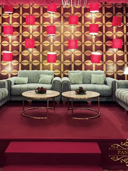 The main seating lounge, featuring a unique backdrop wall with a geometric print and red lampshades, creating a retro-glam vibe.