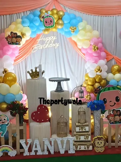 A beautiful Cocomelon setup with a draped backdrop. The pastel and gold balloons, along with all the characters, create a very festive look.