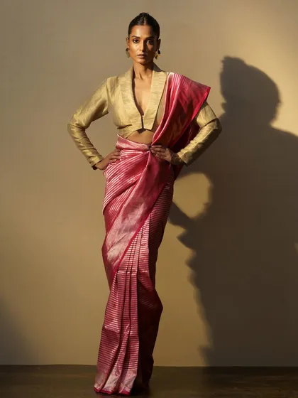 A vibrant pink striped saree paired with a structured gold blouse. This look plays with color and form to create a bold, contemporary statement.