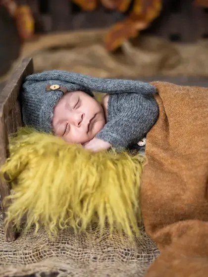 A beautiful sleeping newborn in our rustic campfire setup. We ensure all elements, like the prop campfire, are completely safe and placed to create a magical scene.
