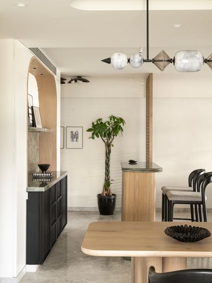This perspective shows the relationship between the dining area and the bar. The sculptural light fixture and custom furniture create a cohesive and highly designed space for entertaining.