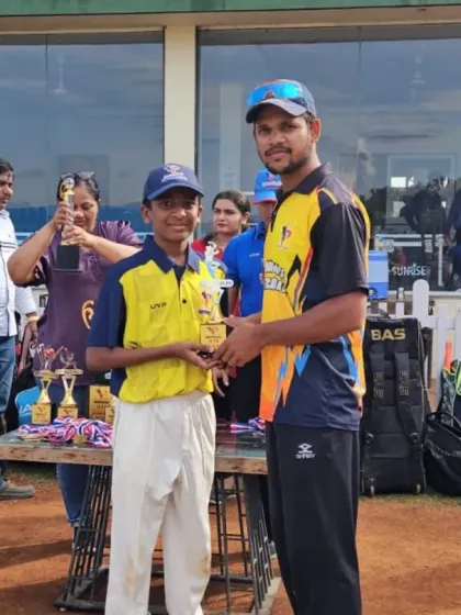 A player from the U-12/U-14 category receives his trophy at our well-equipped ground, with the clubhouse visible in the background.