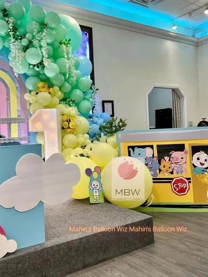 A side view of the pastel Cocomelon setup, highlighting the large "1" marquee light and the custom Cocomelon school bus prop.