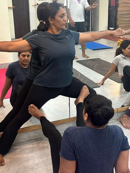Using the mirror for feedback, this pair works on a partner-assisted Warrior II, deepening their understanding of the pose.