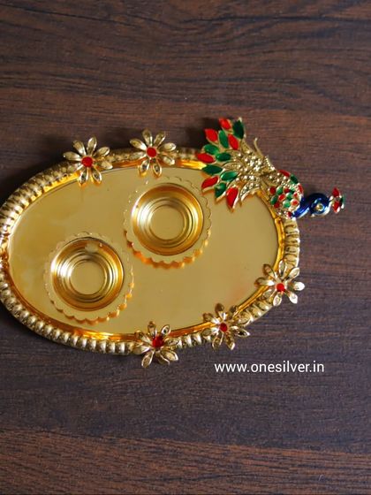 A gold-plated tray with two holders, decorated with a peacock and colorful stones. A very festive piece for your pooja room.