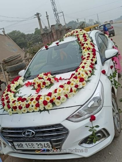 This Hyundai Verna is decorated with a large garland of red and white roses. The design creates a heart shape on the bonnet, perfect for a wedding car.