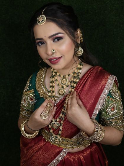 The contrast between the green embroidered blouse and the red silk saree is a classic and timeless combination.