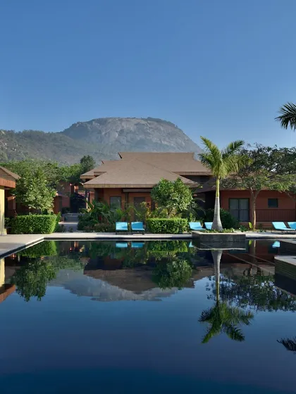 Our stunning pool reflects the sky and surrounding bungalows, with Nandi Hills in the background. This view is a key reason we were named Best Boutique Luxury Resort.