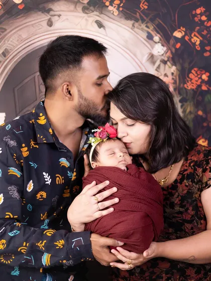 A loving family portrait with parents kissing their peacefully sleeping newborn daughter.