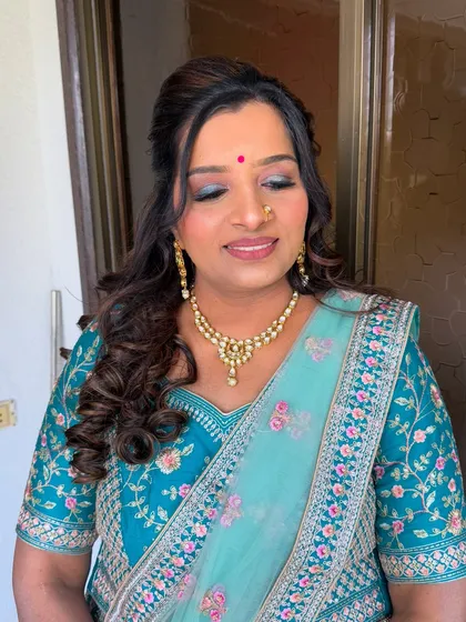 A beautiful soft glam look on a client in a teal saree. The makeup features a shimmery blue-green eyeshadow and a warm lip color.