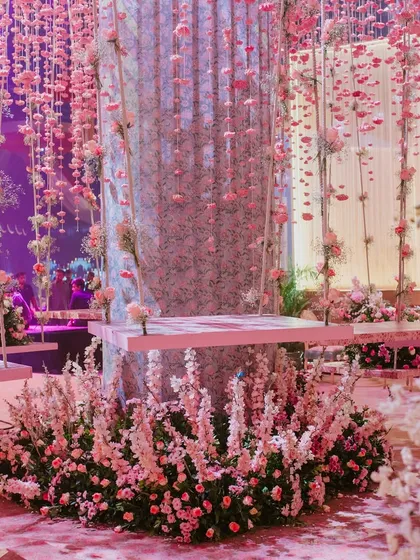 I designed this whimsical space to feel like a daydream. Hanging floral swings are suspended amidst a shower of pink blossoms, creating an interactive and utterly romantic setting that invites guests to become part of the decor.
